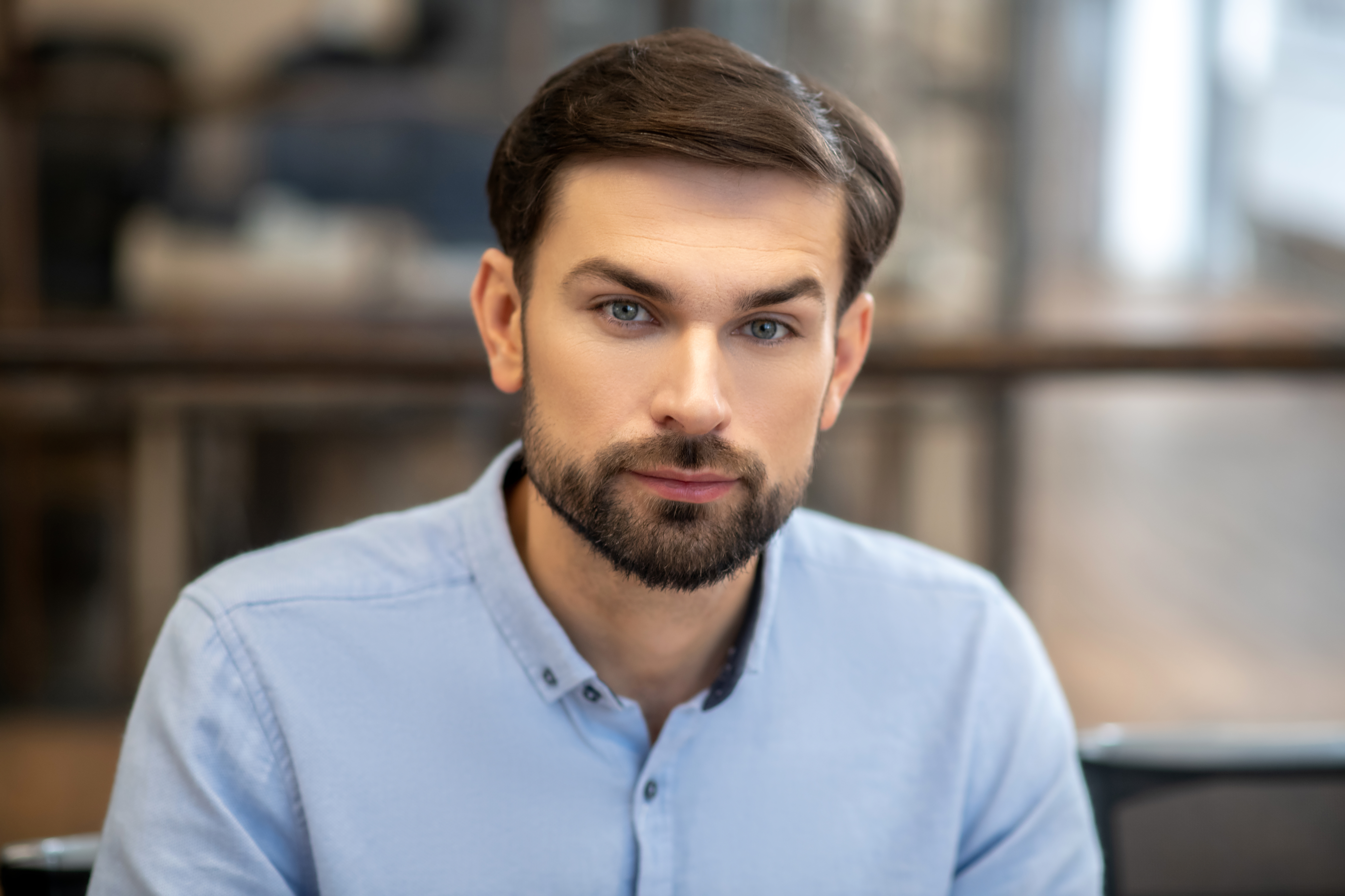 Serious man. Young bearded man in a blue shirt looking serious